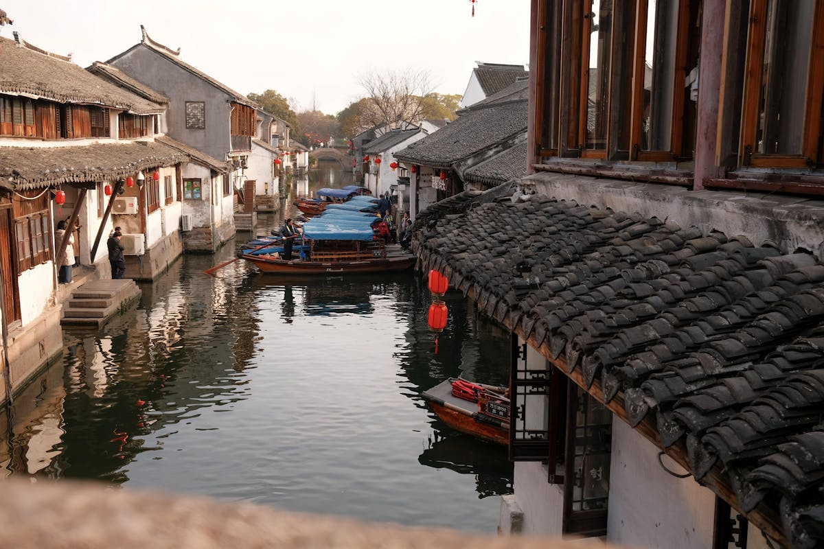 A narrow canal in Zhujiajiao with wooden boats and traditional whitewashed houses lining the water